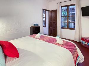 a bedroom with a large white bed with red pillows at Villa Dulé in Antigua Guatemala
