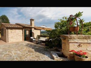 a stone house with a patio and an umbrella at La Casina Toscana in Montepulciano