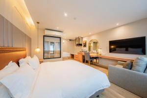 ein Schlafzimmer mit einem großen weißen Bett und einem Schreibtisch in der Unterkunft THEE Bangkok by TH District in Bangkok