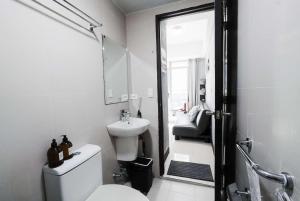 a white bathroom with a toilet and a sink at Cubao Manhattan Heights Residential Condo TA4N - Low Floor Studio with Pool & Balcony, 5 Mins Walk to Gateway Mall & Araneta Coliseum LRT MRT Cubao Quezon City - Staycations by SMS in Manila
