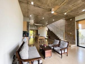 a living room with chairs and a table and a brick wall at Thien An Pine Hill Homestay Hue in Hue