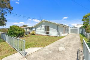 une maison blanche avec une clôture dans une cour dans l'établissement Sanctuary Cottage - Family and Pet Friendly, à Sanctuary Point