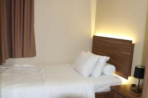 ジャカルタにあるApartment Ambassador 2 Kuninganの白いシーツと枕が備わるベッド1台が備わる客室です。