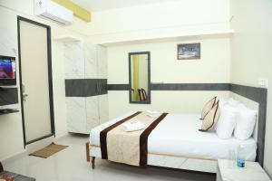 Un dormitorio con una cama y un televisor. en M R Residency Belagavi, en Belgaum