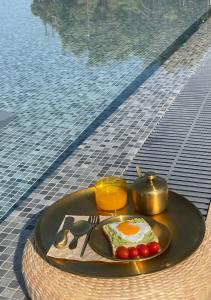 a plate with an egg and fruit on a table next to a pool at Oikos Sani Suites in Sani Beach