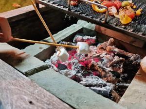 a person cooking food on a grill with chopsticks at Tantai Eco Farm Stay At Khao Yai in Ban Sap Noi