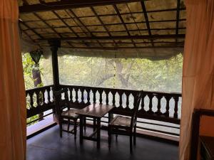 a table and chairs on a balcony with a window at Khaama Kethna Eco Sustainable Village in Agonda