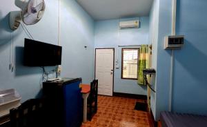 a blue room with a desk and a television and a door at JaiSabai Homestay in Mae Ai