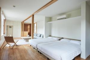 a white bedroom with two beds and a chair at Shibi in Nara