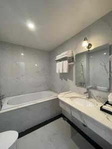 a white bathroom with a tub and a sink at Lotus Hotel & Apartment in Hai Phong
