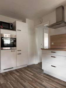 une cuisine avec des armoires blanches et un plancher en bois dans l'établissement Design Apartment Bali in Rödersheim-Gronau, à Rödersheim-Gronau