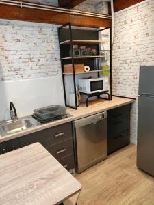 a kitchen with a counter with a sink and a refrigerator at Le PTit Atelier, Appartement cosy à Champagnole in Champagnole +2 photos