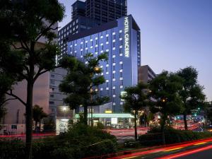 a tall blue building with trees in front of a street at Hotel Gracery Osaka Namba in Osaka