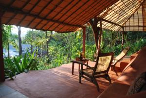 a porch of a house with a chair and a table at Khaama Kethna Eco Sustainable Village in Agonda