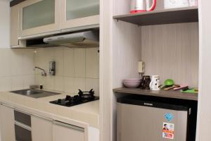 a small kitchen with a sink and a stove at Cozy and Warm Studio at Grand Sentraland Karawang Apartment By Travelio in Karawang