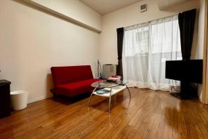 a living room with a red couch and a glass table at 302便利な立地札幌駅が徒歩7分の超人気で美室女性に人気 in Kita-rokujō