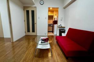 a living room with a red couch and a glass table at 302便利な立地札幌駅が徒歩7分の超人気で美室女性に人気 in Kita-rokujō