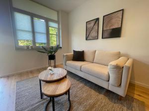 City Lofts Tegernsee - Moderne Studios zentral gelegen في باد ويسي: غرفة معيشة بها أريكة وطاولة