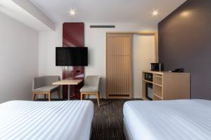 a hotel room with two beds and a table and chairs at Hotel Vista Kanazawa in Kanazawa
