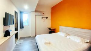 a bedroom with a white bed with an orange wall at Hi-Inn in Miri