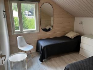 Un dormitorio con una cama, un espejo y una silla. en Villa Jämsä, en Säyrylä