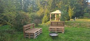 two wooden benches and a gazebo in the grass at Wohnmobilstellplatz in Mecklenburg-Vorpommern - ab Juni Dixi WC in Carpin