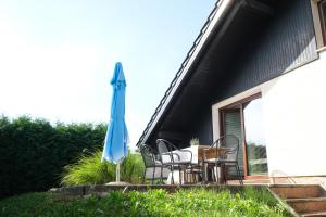 a patio with a table and a blue umbrella at Hiša Perla in Boštanj