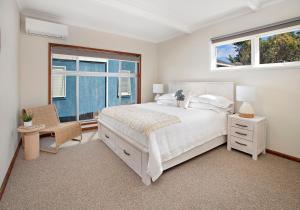 a bedroom with a white bed and two windows at Beach House on Johnson in Kiama Downs +7 photos
