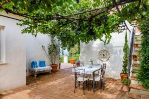 patio ze stołem i krzesłami pod drzewem w obiekcie Casa Sole di Toscana con grande terrazza panoramica, giardino e vasca relax idromassaggio w mieście Monterotondo