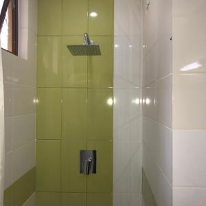 a bathroom with a shower with green and white tiles at Saninro Hotel - Ragama in Ragama