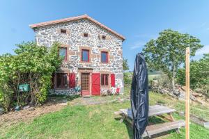 una vecchia casa in pietra con porte rosse su una collina di La Maison de Freda - Maison avec vue montagne a Beauregard