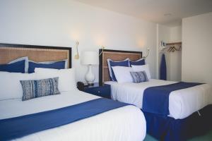 a bedroom with two beds with blue and white pillows at Mylo Hotel in Daly City