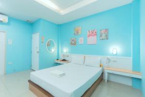 a blue room with a bed and a desk at โรงแรมนั่งเล่น in Chon Buri