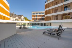 a patio with chairs and a swimming pool on a building at Apartament Baltic Waves Basen Siłownia Sauna by Rent like home in Międzyzdroje