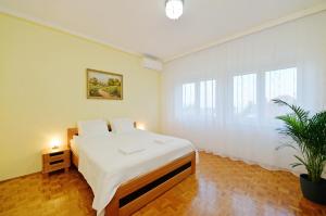 a white bedroom with a bed and a plant at Blackbird Apartment in Balatonfüred
