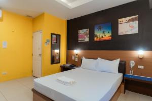 a bedroom with a large bed and yellow walls at โรงแรมนั่งเล่น in Chon Buri