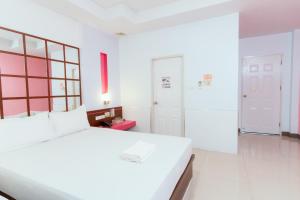 a white bedroom with a large white bed and a door at โรงแรมนั่งเล่น in Chon Buri