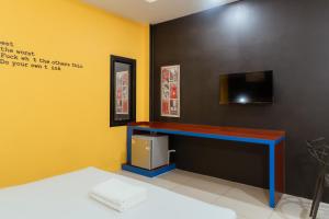 a room with a wall with a tv and a desk at โรงแรมนั่งเล่น in Chon Buri