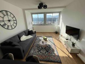 a living room with a black couch and a clock at Plein centre-ville T2 refait à neuf in Aix-les-Bains