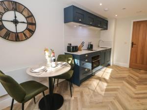 a kitchen with a table and a clock on the wall at Rock Mill Apartment in Eyam