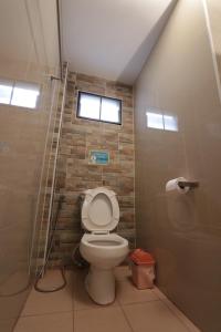 a bathroom with a toilet and a brick wall at โรงแรมนั่งเล่น in Chon Buri