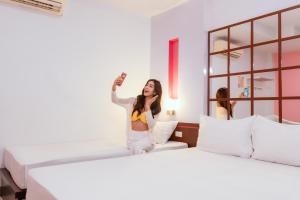 a woman sitting on a bed taking a picture of herself at โรงแรมนั่งเล่น in Chon Buri