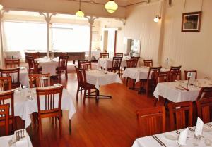 a dining room with white tables and wooden chairs at Railway Hotel in Gympie