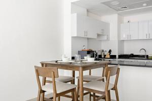 a kitchen with a wooden table and four chairs at Peaceful and Spacious Apartment in Saadiyat in Abu Dhabi