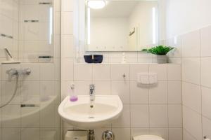 a white bathroom with a sink and a shower at Ferienwohnung Oberdeck in Schilksee +13 photos