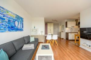 a living room with a gray couch and a kitchen at Ferienwohnung Oberdeck in Schilksee