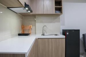a kitchen with a sink and a black refrigerator at Comfort 2BR at Daan Mogot City Apartment By Travelio in Jakarta