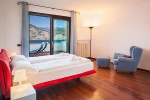 a bedroom with a bed and a chair and a window at Villa Manuela-Vista Lago in Brenzone sul Garda