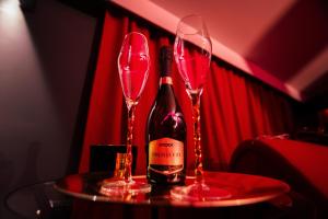 two wine glasses on a table with a bottle of wine at Red Palace Apartament BDSM in Bydgoszcz
