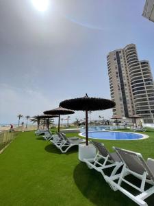 a row of chairs and umbrellas next to a pool at Espacio2,1a línea,jacuzzi,piscina in Cullera